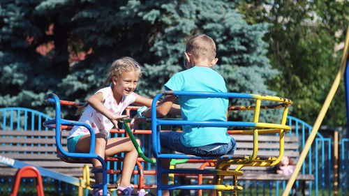 Happy children, a girl and a boy of seven, ride on a swing, on a hot summer day. slow motion