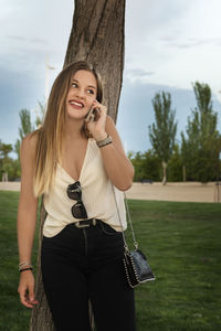 Portrait of smiling young woman standing against trees