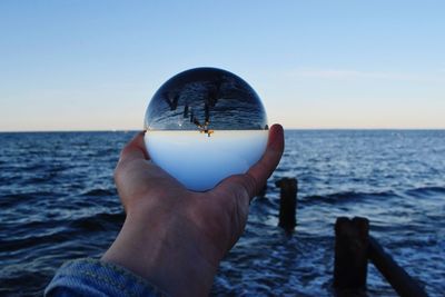 Midsection of person holding sea against sky