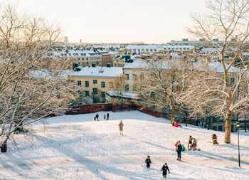 People in snow covered park against sky