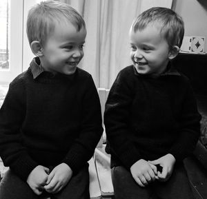 Cute twin boys smiling while sitting at home