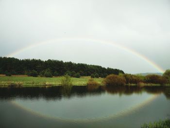 Scenic view of rainbow over lake against sky