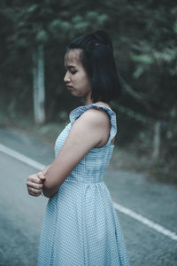 Side view of young woman standing on road