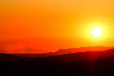 Scenic view of silhouette mountains against romantic sky at sunset