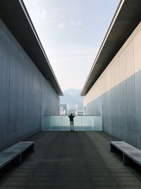 Rear view of man walking on building against sky