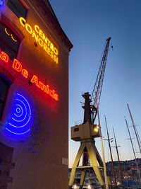 Low angle view of illuminated information sign against clear sky