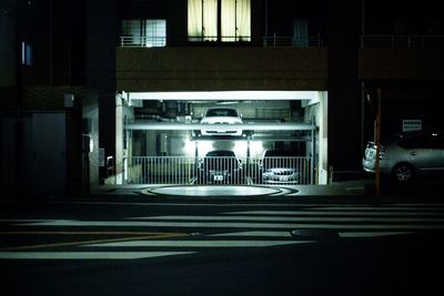 Illuminated building by road in city at night