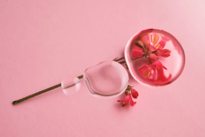 Three drops of cosmetic transparent gel on a pink background. the texture of the serum.