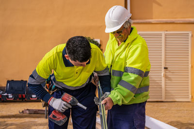 Group of male technicians in uniform working with alternative solar panels and preparing for installation near residential building