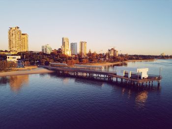 Scenic view of river by buildings against clear sky