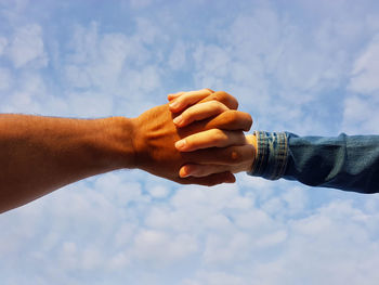 Cropped hand of man against sky