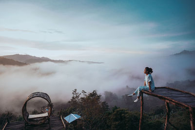 Rear view of man standing on mountain against sky