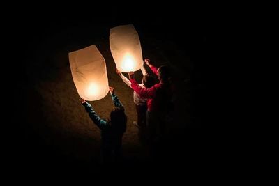 Illuminated light bulbs hanging at night