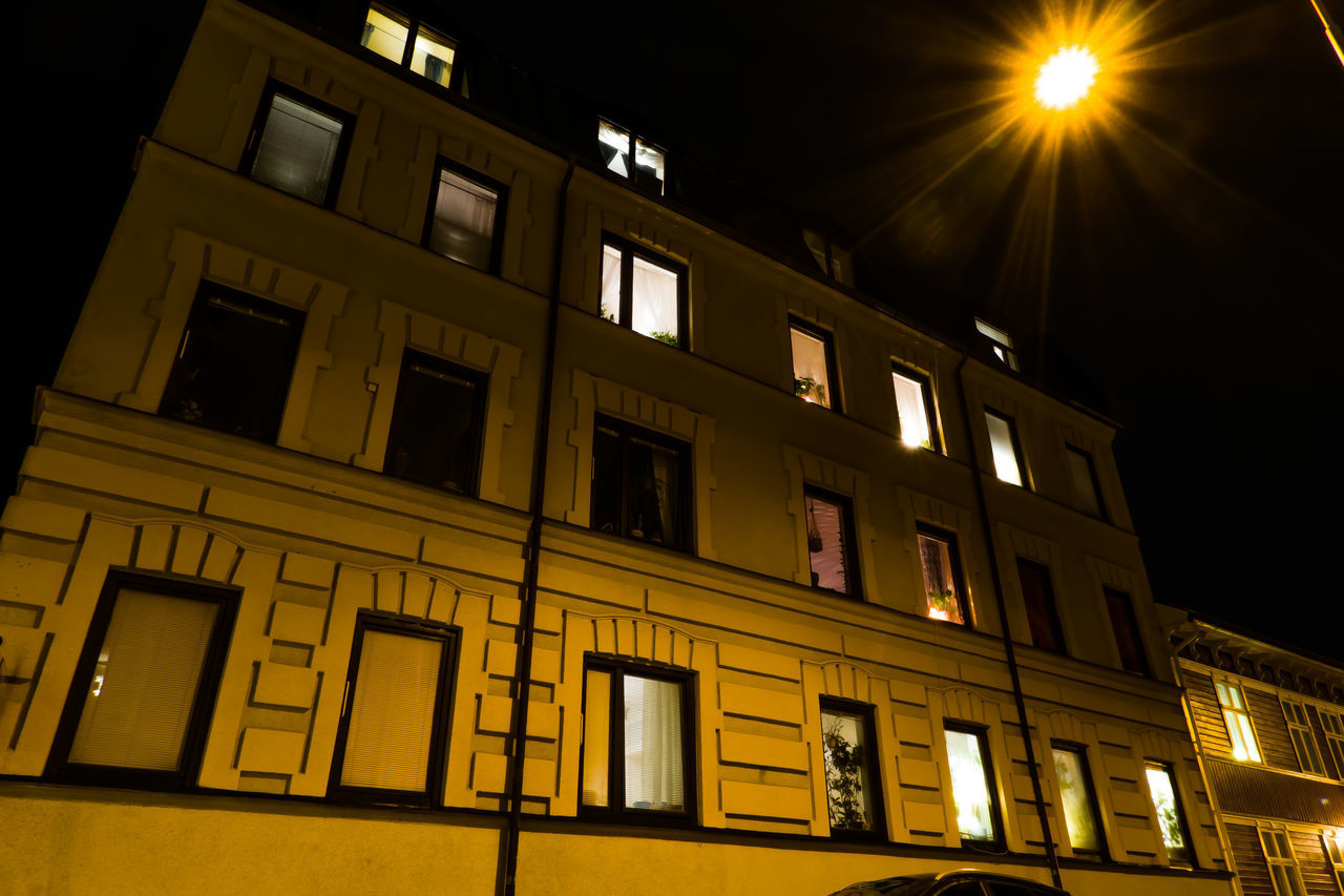 LOW ANGLE VIEW OF ILLUMINATED RESIDENTIAL BUILDING AT NIGHT