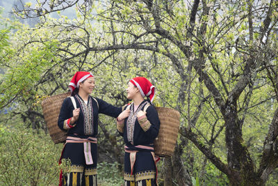 Young couple standing by tree against plants