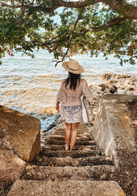 Young woman in beach clothes on stairs by sea. summer, lifestyle, vacation.