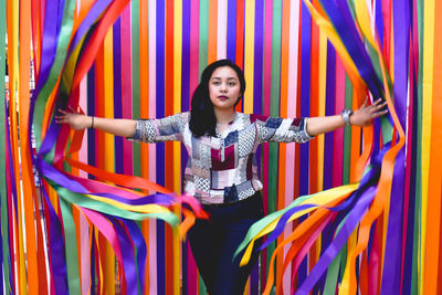 Full length of smiling young woman standing against multi colored wall