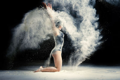 Full length of woman dancing against black background