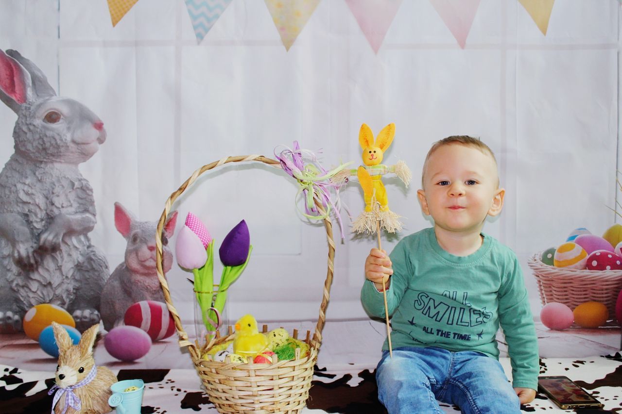 animal representation, indoors, childhood, real people, casual clothing, easter, cute, basket, one person, leisure activity, multi colored, day, mammal