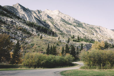 Scenic view of road by mountains against clear sky