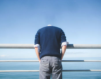 Rear view of man looking at sea against clear sky