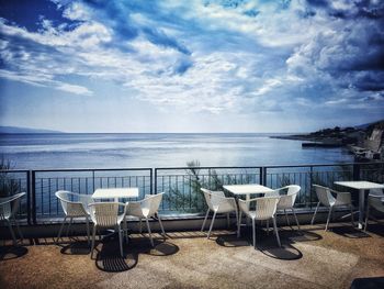 Chairs and table at beach against sky