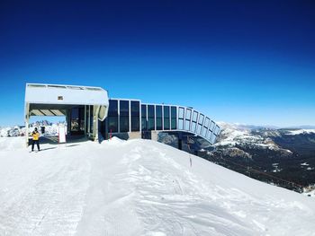 Built structure on snow covered landscape against clear blue sky