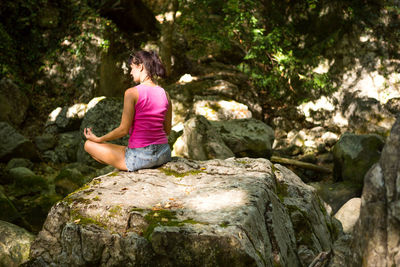 Rear view of woman sitting on rock