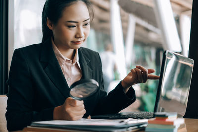 Young woman using mobile phone while sitting on table