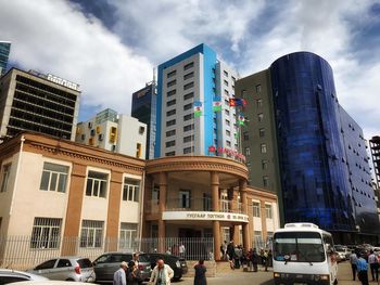 Low angle view of skyscrapers against cloudy sky