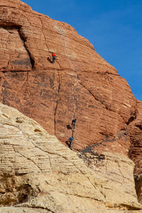 Low angle view of man climbing on rock against sky. red rock canyon, nevada 