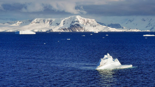 Scenic view of sea and snowcapped mountains against sky