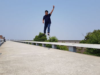 Full length of man jumping against clear sky