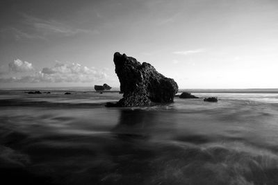 Rock formation on beach against sky