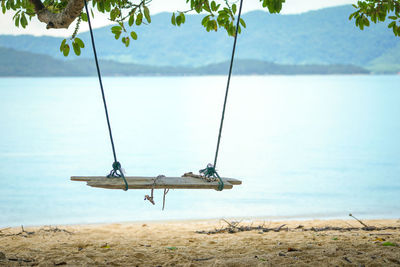 View of swing in sea against sky