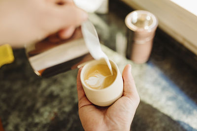 Young man preparing latte in kitchen