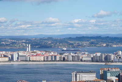 Cityscape by sea against sky