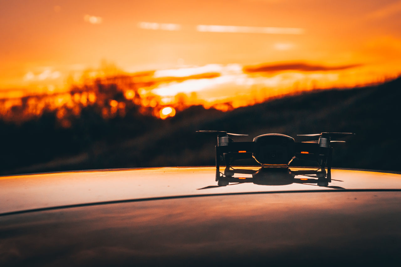 CLOSE-UP OF CAMERA ON TABLE AGAINST SUNSET SKY