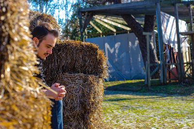 Thoughtful man sitting by hay bales on field