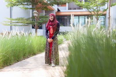 Portrait of woman in hijab standing on footpath at park
