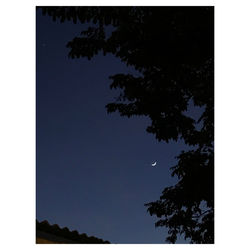 Low angle view of silhouette trees against clear blue sky