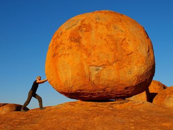 Full length side view of woman pushing huge rock