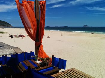 Deck chairs on beach against sky