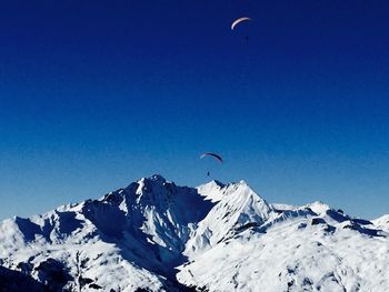 Bird flying over mountain against clear blue sky