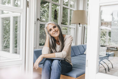 Smiling woman sitting on lounge in winter garden