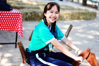 Portrait of smiling woman sitting on outdoor play equipment at playground