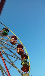 Low angle view of ferris wheel against clear blue sky