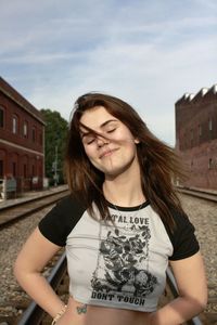 Portrait of smiling young woman standing against sky