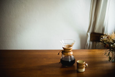 High angle view of black coffee in glass container on wooden table