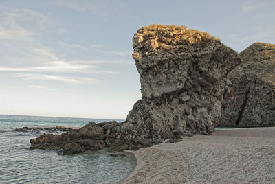 Rock formation on beach against sky